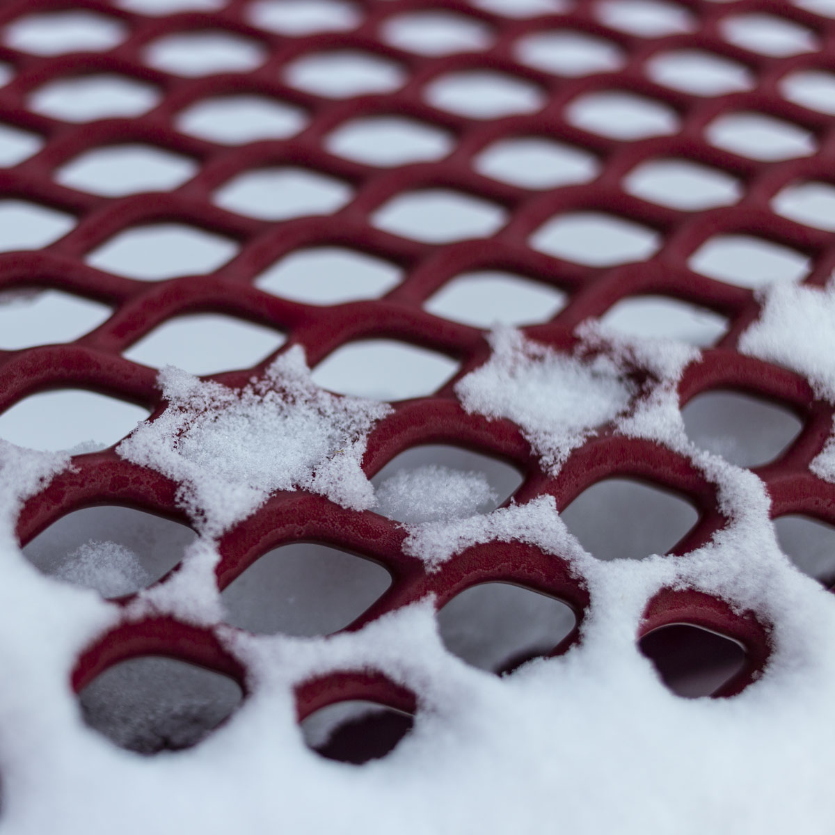 The main subject, a patch of star shaped snow on a park bench,is isolated using background blur.