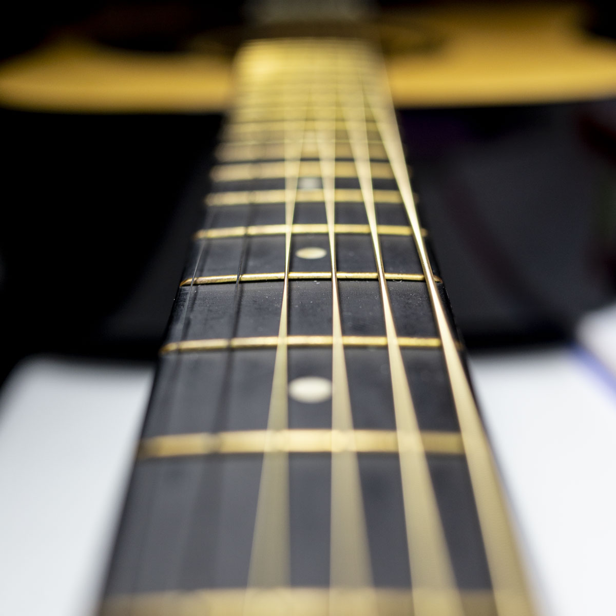 This image uses small aperture values to create shallow depth-of-field that blurs the guitar strings viewed down the fretboard. The point of focus stands out easily with the blurred surroundings.