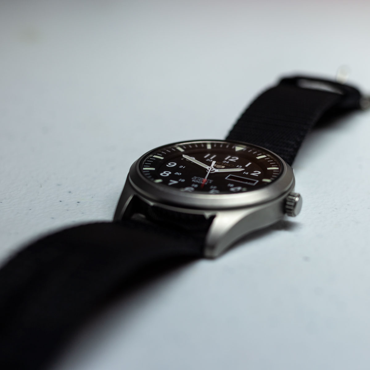 This image of a watch on a white background uses a low angle and shallow depth-of-field to give the watch an out of the ordinary look.