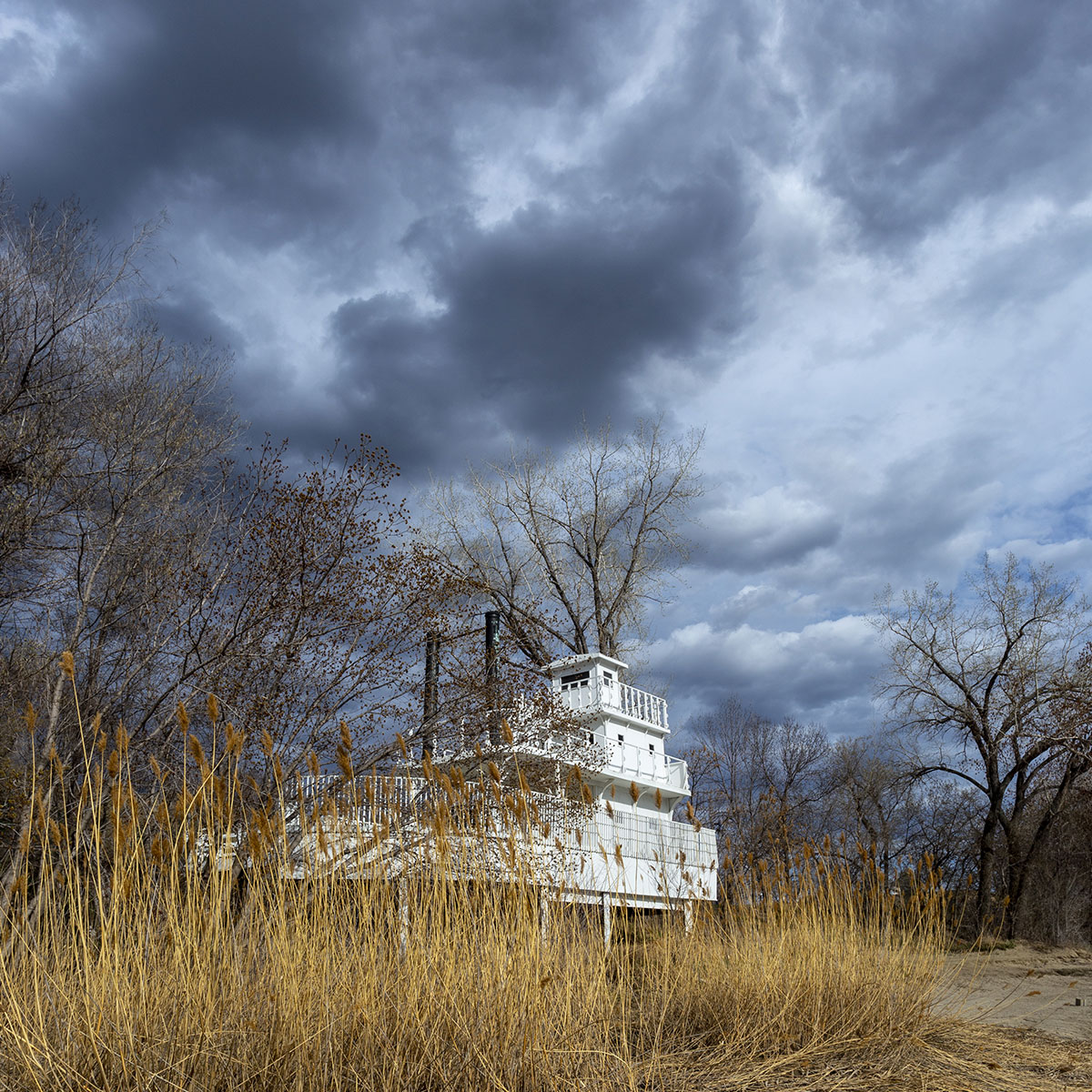Golden reeds and cloudy skies frame a static display of a steamboat at Steamboat Park Bismarck, North Dakota on the banks of the Missouri River.