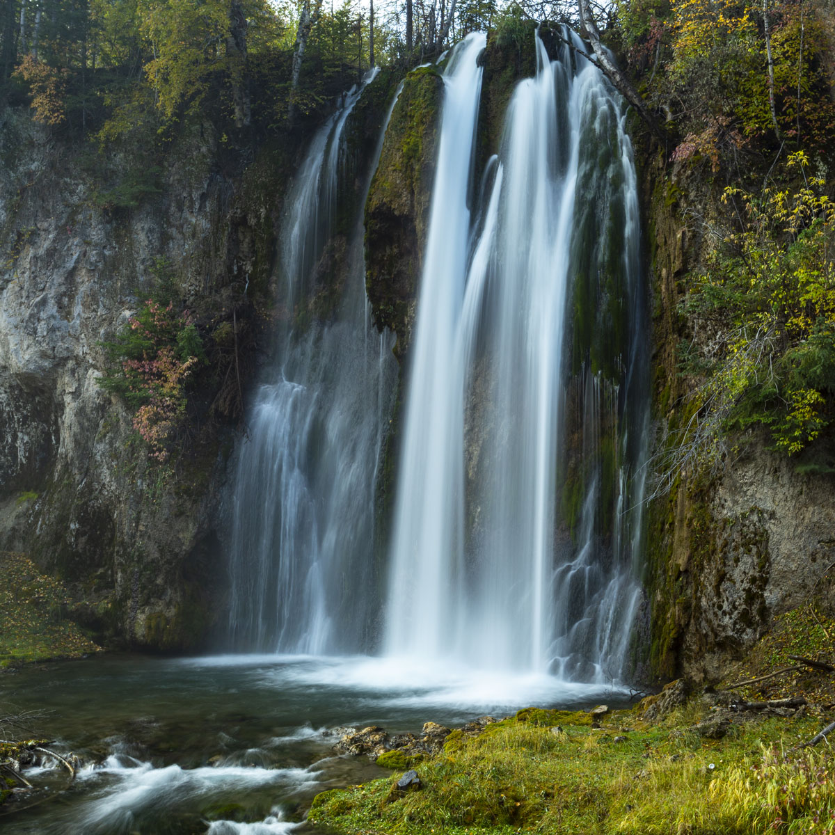 Spearfish Falls fills the picture appearing smooth and silky white against a backdrop of the canyon wall adorned in yellow, orange and green foliage.