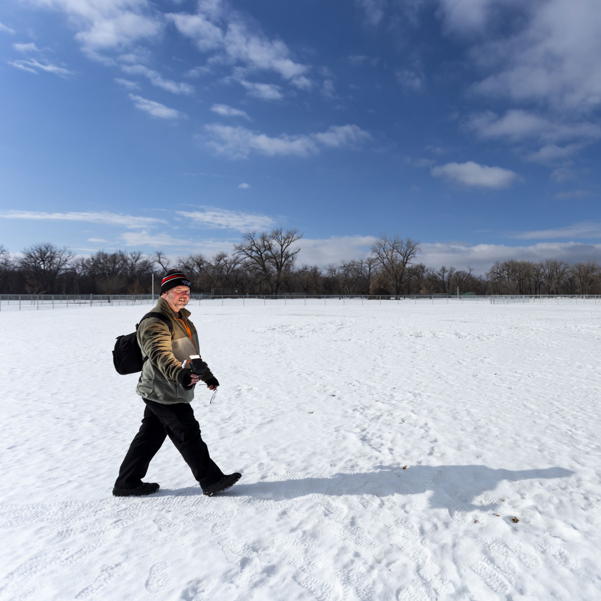 Positioned in the left third of this photo the author is show walking left to right across a snow covered sports field. Positioning your subject this way helps to show motion in the picture.